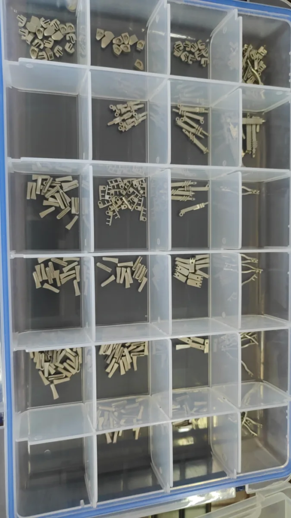 micro-mim-sorted-parts Micro-MIM parts sorted by type: pins, brackets, connectors, and fasteners — each produced to tight tolerances
